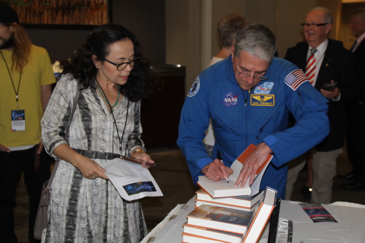 Retired astronaut Don Thomas signs his book for an Ascension Flight attendee.