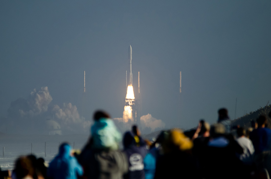 people watching rocket space launch from view deck