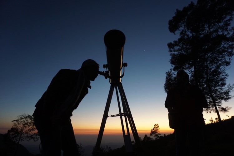 man with astronomy telescope looking at the stars