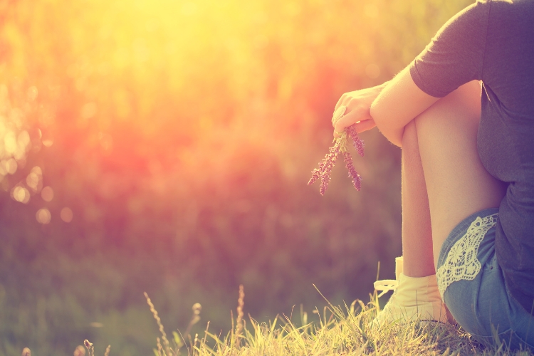 young woman at sunset holding a flower