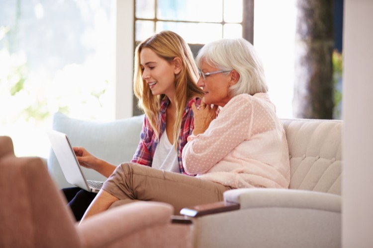 granddaughter and grandmother watching old videos on a laptop