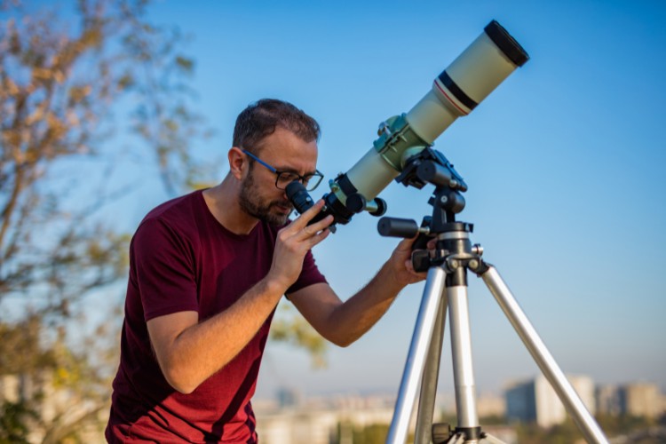 amateur astronomer looking into telescope