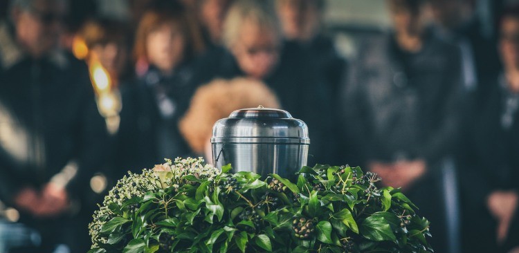 metal urn at a funeral with people mourning at the background