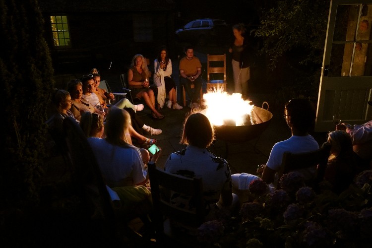 Family and friends sharing memories around a firepit in an informal memorial service