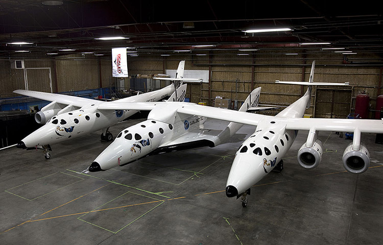 The Scaled Composites SpaceShipTwo spaceplane (central fuselage) resting under its mothership, White Knight Two, inside a hangar in Mojave, Ca., USA